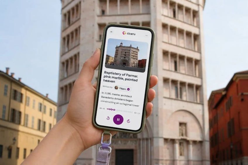 A hand holding a smartphone displaying information about the Baptistry of Parma, a pink marble building painted in white. 1