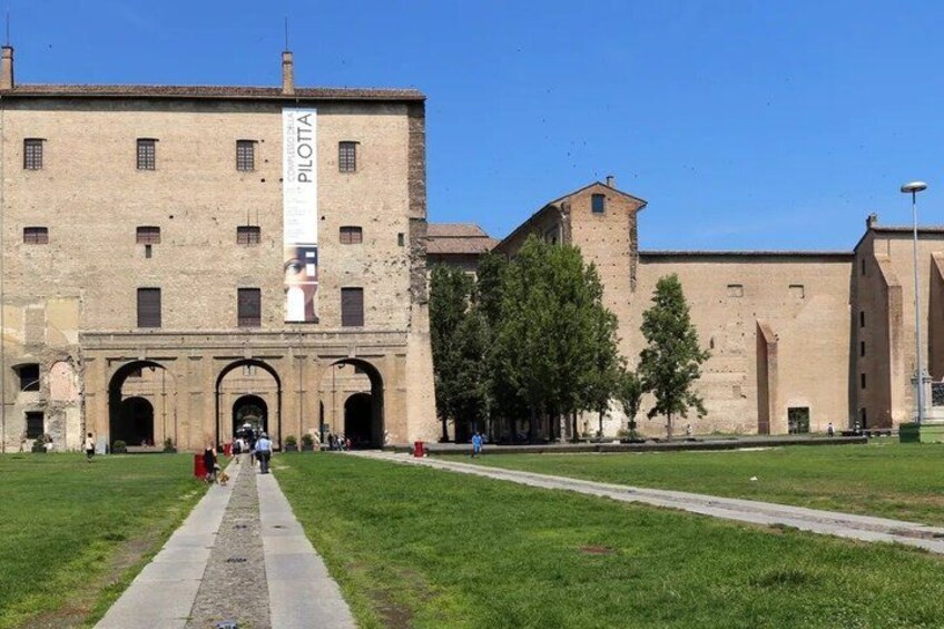 A historic building with a large banner, a paved pathway, and green grass. 3