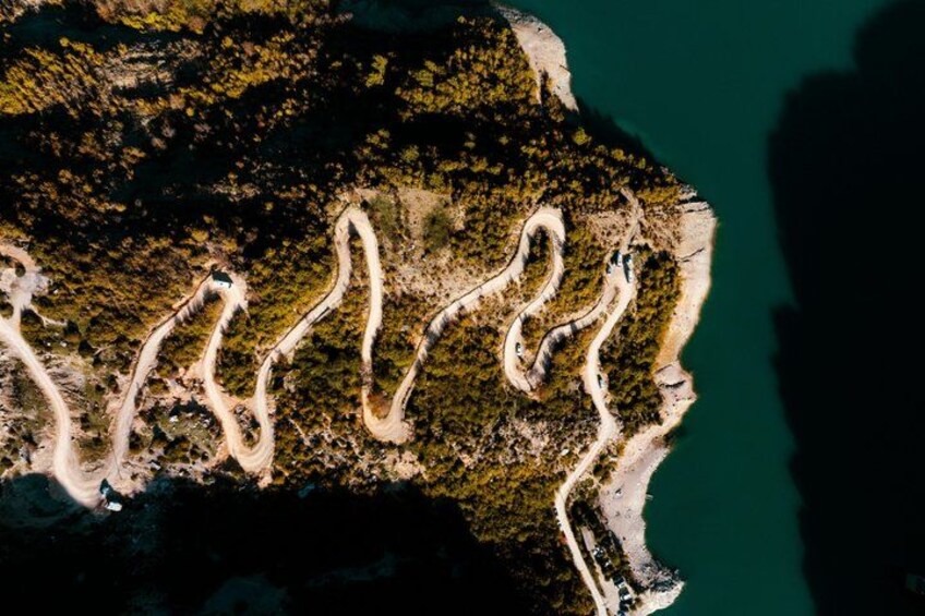 A winding road along a coastal area with dense vegetation and a beach. 4