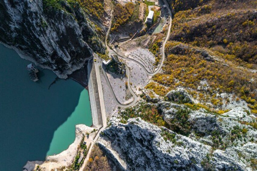 A mountainous landscape with a dam, a winding road, and a body of water. 2