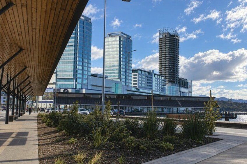 A modern building with a glass facade, a covered walkway, and a mountainous backdrop. 3