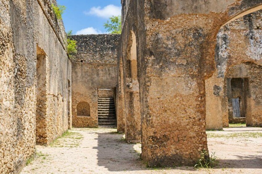 An ancient stone building with arched doorways and a central staircase. 2