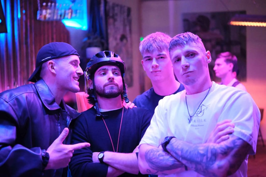 A group of people in a dimly lit indoor setting with purple lighting. 2