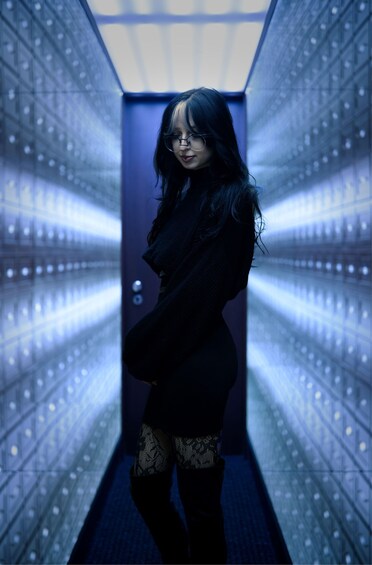 A person standing in a hallway with a grid of lights on the walls. 3