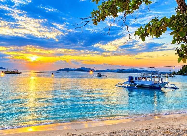 Un atardecer sobre un mar tranquilo con barcos y una playa. 4