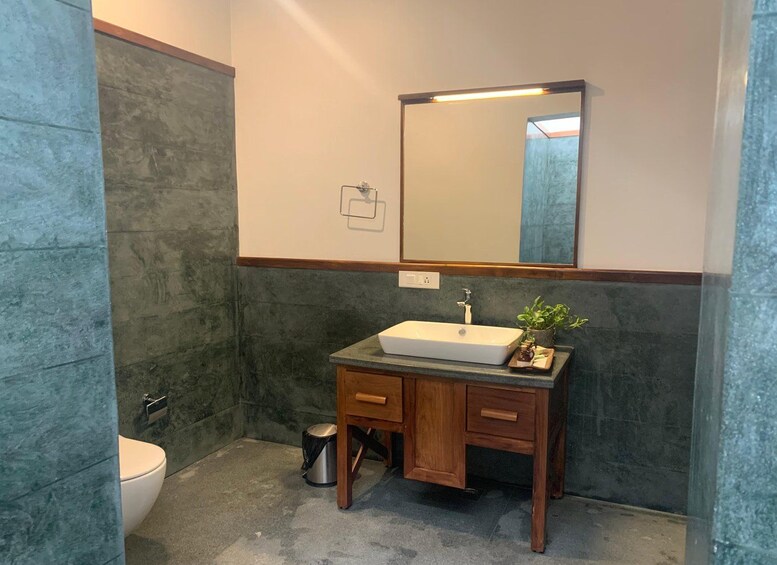Un baño con lavamanos blanco, mueble de madera y espejo. 5