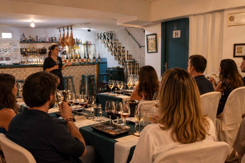 A group of people seated at a table in a restaurant, with a bartender serving drinks. 3