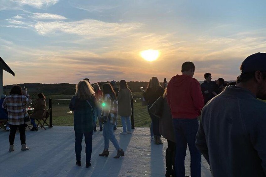 A group of people standing on a snow-covered ground, facing a sunset. 2