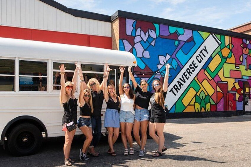 A group of people posing in front of a mural with the text 'TRAVERSE CITY'. 1