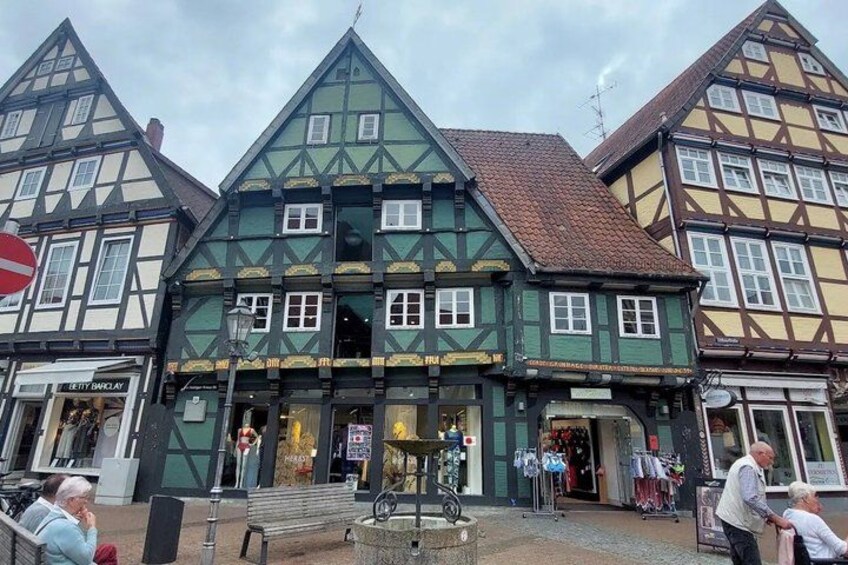A traditional half-timbered building with a green facade and a red-tiled roof. 3