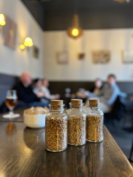 A restaurant interior with wooden tables, bottles of grains, and patrons dining. 4