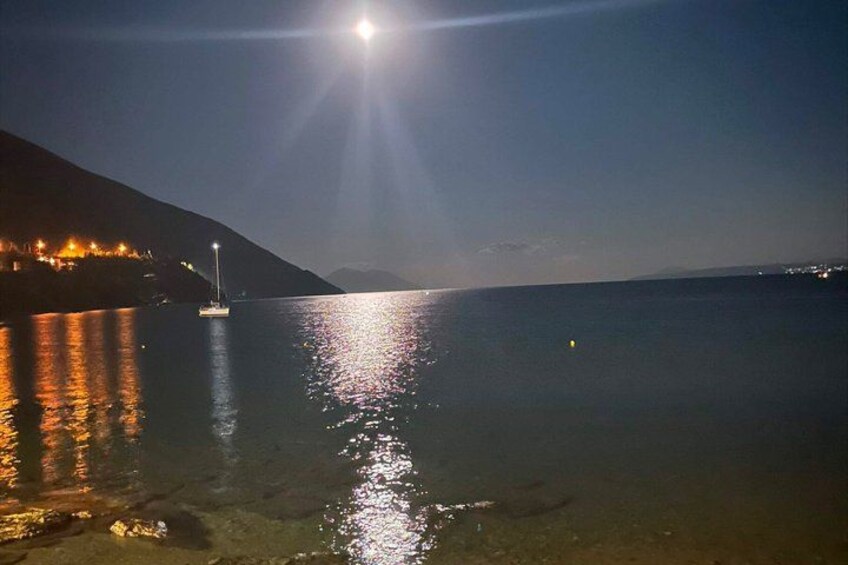 A calm lake at night with a boat and a distant mountain. 2