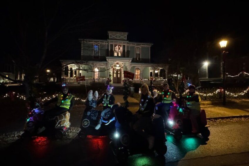 A group of people on motorcycles with lights, gathered in front of a lit-up building at night. 4