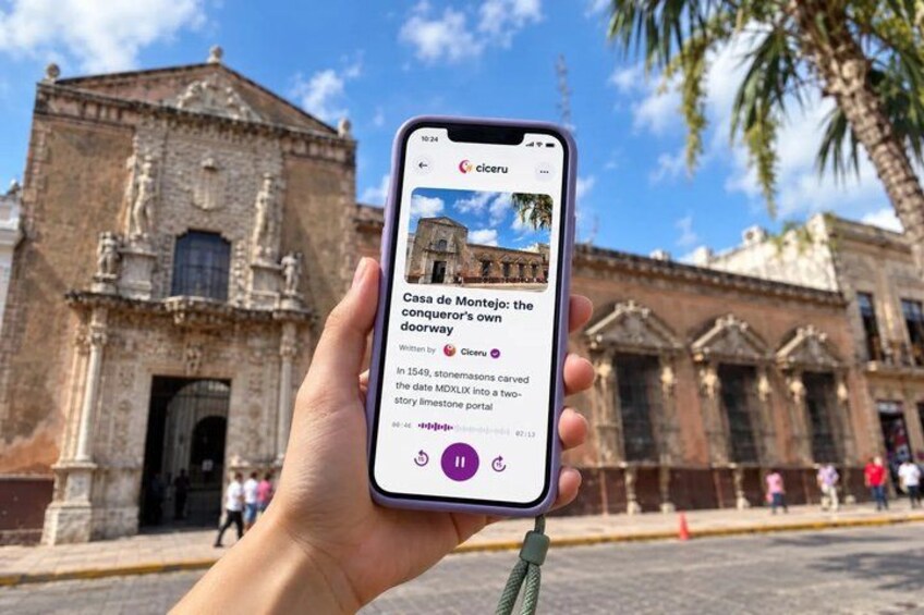 A hand holding a smartphone displaying a photo of a historic building with a caption. 1