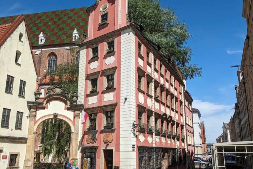 A historic building with a red and white facade, an arched entrance, and a green-tiled roof. 5
