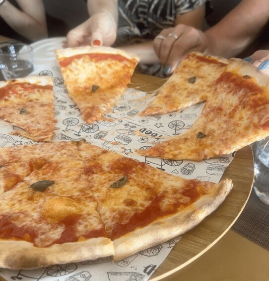 Pizza med manglende skiver på en papirtallerken med tegninger, stående på et spisebord. 4