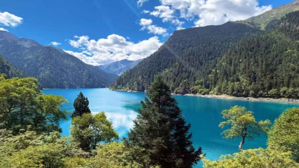 Een turquoise meer, omringd door beboste bergen, onder een heldere lucht. 1
