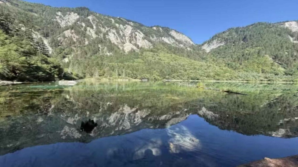 Een bergmeer met heldere weerspiegelingen, omgeven door beboste heuvels. 2