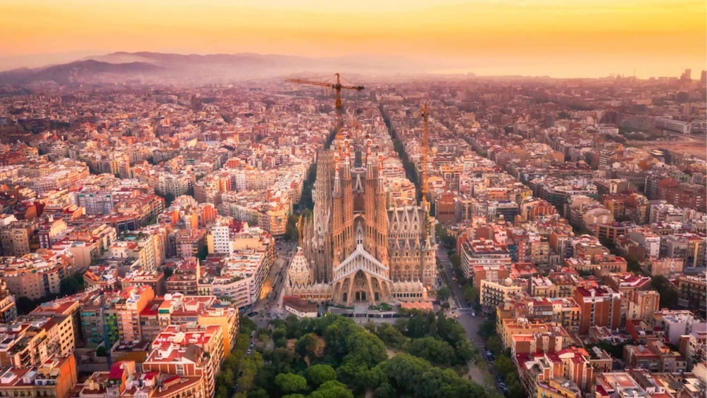 A cityscape with a prominent cathedral at the center, surrounded by dense urban buildings and a construction crane in the distance. 2