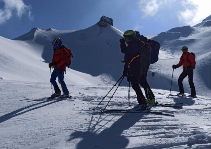 Three skiers on a snowy mountain with a clear sky. 3