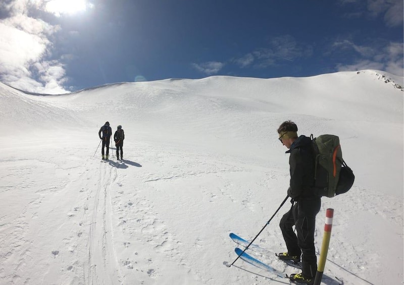 A snowy mountain slope with skiers and a clear sky. 2