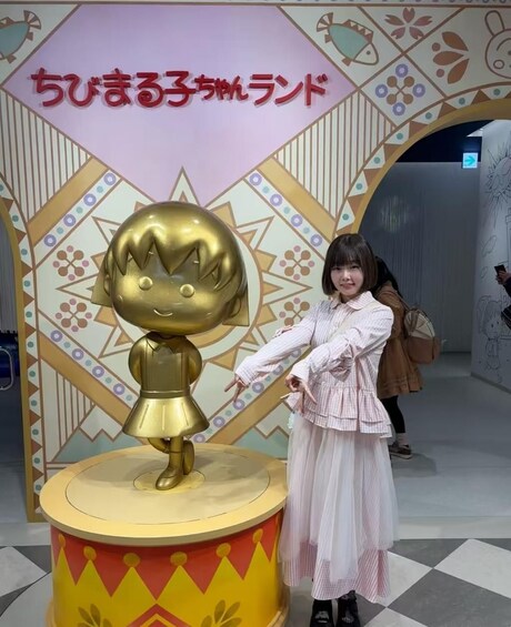 A person posing in front of a colorful backdrop with a golden statue and Japanese text. 4