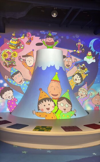 A stage with cartoon characters in party hats, a disco ball, and a large ice cream cone structure. 3