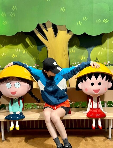 A person sitting on a bench with two large cartoon character figures on either side. 1