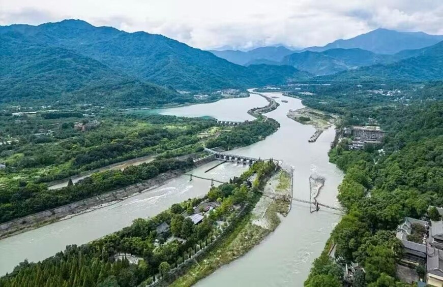 A river winding through a mountainous landscape with a bridge and a dam. 3