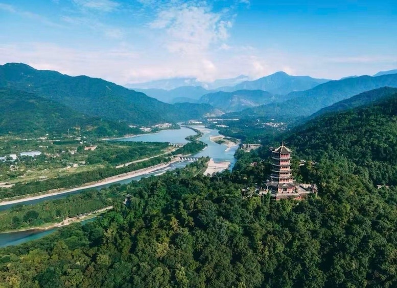 A river winding through a mountainous landscape with a pagoda-like structure on a hill. 1
