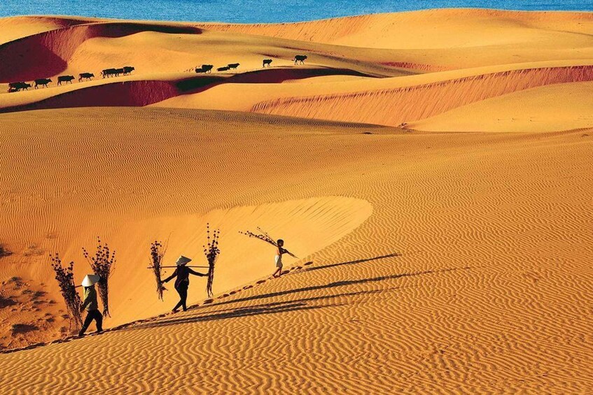 Un paysage désertique avec des dunes de sable et un groupe de personnes qui marchent. 3