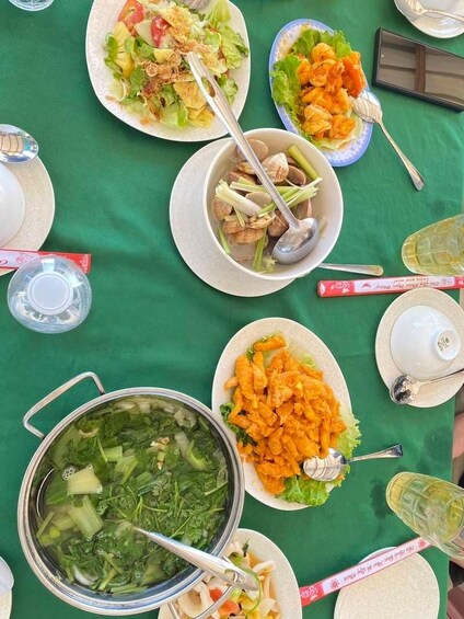 Une table dressée avec divers plats, notamment un bol de soupe, des assiettes de légumes et une assiette de plats frits. 2