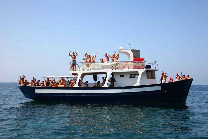 Un barco con gente a bordo, algunos de pie y saludando, otros sentados, en un mar tranquilo. 3