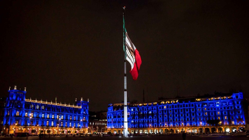 Un edificio con luces azules iluminadas y un asta con una bandera. 4