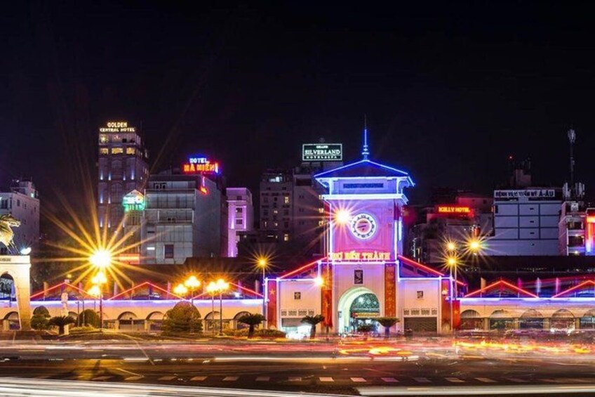 A brightly lit urban area with a prominent clock tower and illuminated signage. 4