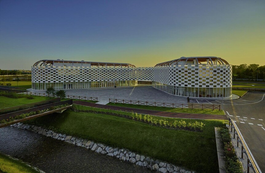 A modern architectural structure with a checkered pattern, surrounded by a landscaped area with a pathway and a small water feature. 2