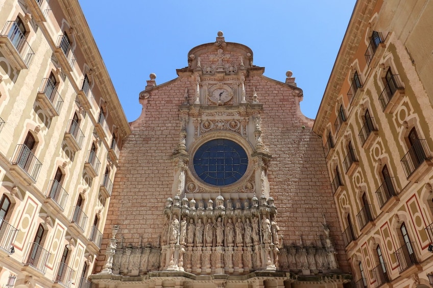 A historic building with a clock tower, ornate facade, and statues. 4