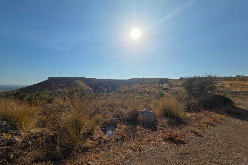 Un paisaje seco y cubierto de hierba con cielo despejado y un sol brillante. 5
