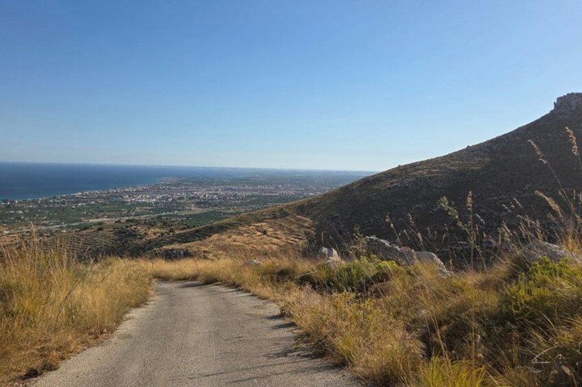 Una carretera serpenteante que lleva a un pueblo costero, con vista al océano y una colina al fondo. 2