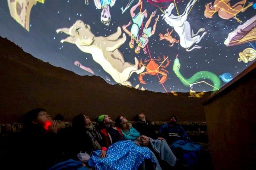 A group of people watching a projection of animated characters on a curved ceiling. 1