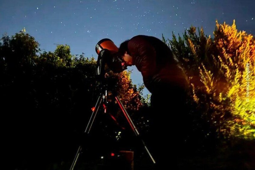 A person using a telescope at night. 3