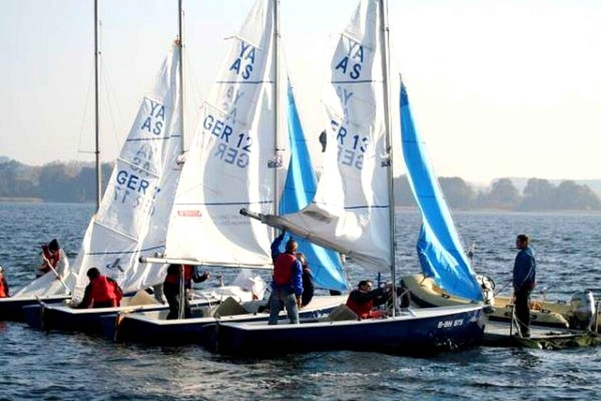 A group of sailboats on a body of water with people on board. 4