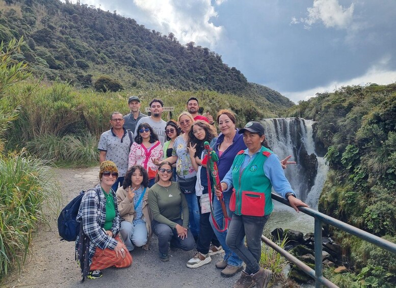 A group of people posing in front of a waterfall with lush greenery in the background. 3