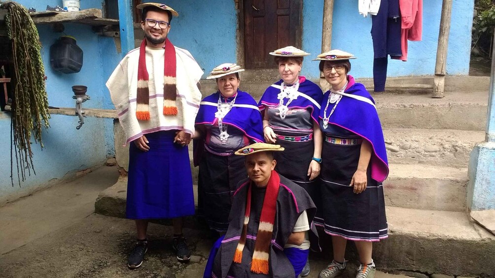 A group of people in traditional attire standing in front of a blue building with steps. 5