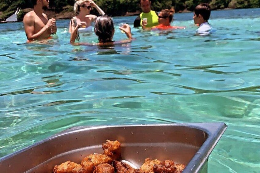 A swimming pool with people in the water and a metal tray with fried food in the foreground. 5