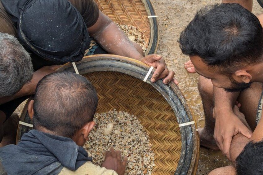 People working with a large woven basket filled with small objects, possibly grains or seeds. 1