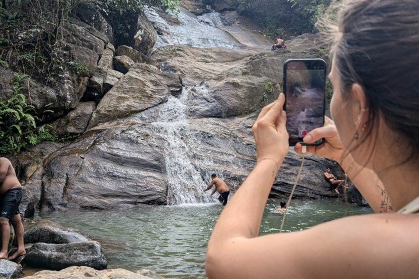 A waterfall, rocky terrain, and people swimming in a natural setting. 3