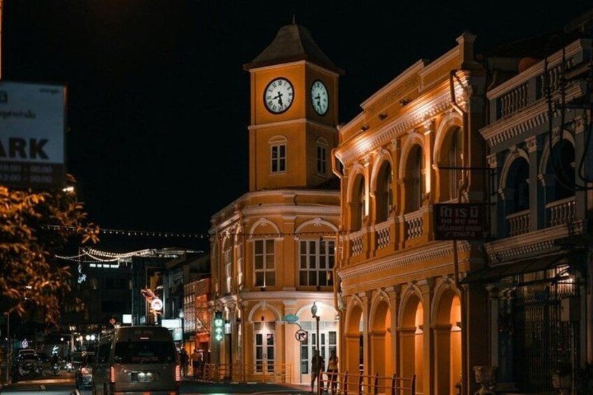 A historic building with a clock tower, illuminated by warm lighting, and a street with vehicles and pedestrians. 4