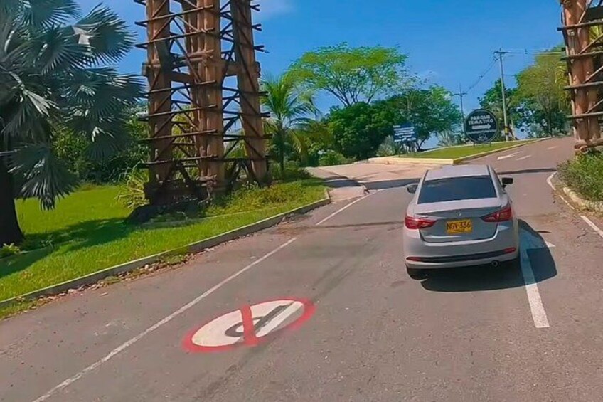 A road with a no parking sign, a car, and palm trees. 1