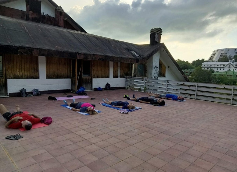 A group of people lying on mats on a rooftop with a building in the background. 2